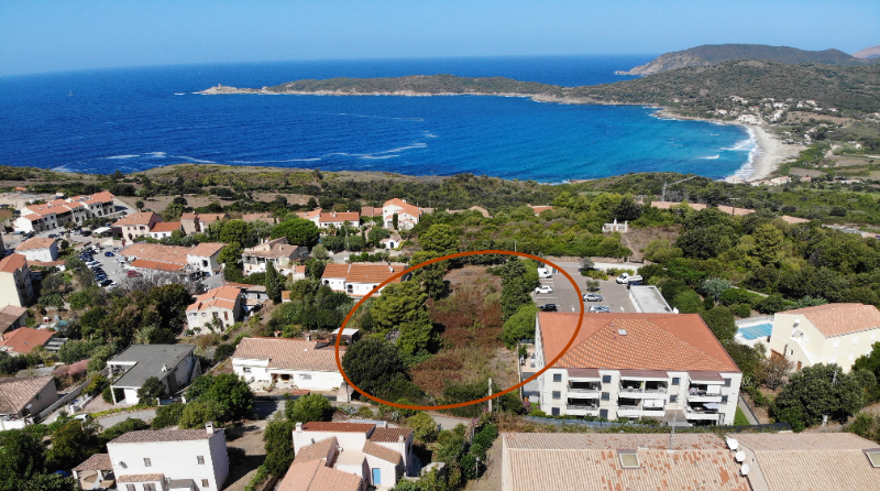 Vue aérienne du terrain de la résidence, cerclé, entre village et baie